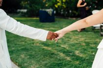 Hand des unkenntlichen Bräutigams umarmt Braut im weißen Kleid. — Stockfoto