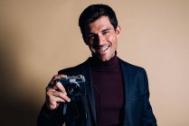Молодий чоловік в студії тримає старовинну камеру — стокове фото