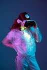 Mujer con gafas VR en luz de neón sobre fondo azul - foto de stock