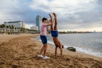 Два спортсмена делают стойку на руках на пляже — стоковое фото