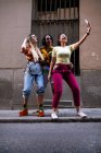 Grupo de jovens em trajes da moda rindo e tirando selfie enquanto se diverte na rua da cidade — Fotografia de Stock