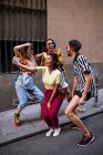 Grupo de jovens em trajes da moda rindo e tirando selfie enquanto se diverte na rua da cidade — Fotografia de Stock