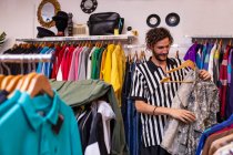 Веселий чоловік вибирає одяг та аксесуари в магазині — стокове фото