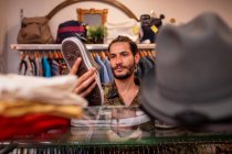 Hombre alegre eligiendo ropa y accesorios en la tienda - foto de stock