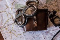 Planejando uma viagem em um mapa com óculos de motocicleta vintage e prismático velho — Fotografia de Stock