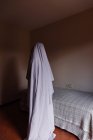 Человек, замаскированный под призрака на Хэллоуин стоя в комнате — стоковое фото