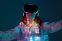 Жінка торкається повітря в окулярах VR в неоновому світлі — стокове фото