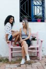 Two girls sitting on a bench in the street — Stock Photo