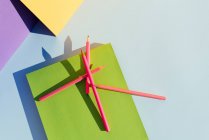 Pinkfarbene Bleistifte auf grünem Buch, im Raum geometrischer Formen und starker Schatten. Zurück zum Schulkonzept — Stockfoto