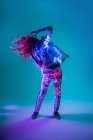Woman dancing in neon light on blue background — Stock Photo