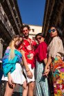 Schöner junger Mann, der sich mit drei Frauen umarmt, trendige Kleidung trägt und an sonnigen Tagen auf der Straße steht — Stockfoto