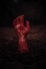 Рука зомби выходит из-под земли на темном фоне — стоковое фото