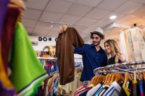 Handsome man choosing stylish shirt while spending time in small store with girlfriend — Stock Photo