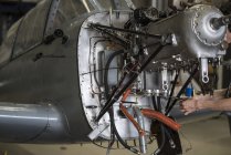 Hände eines Flugzeugmechanikers reparieren Motor eines Kleinflugzeugs im Hangar — Stockfoto