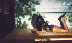 Jovem sensual mulher em uma peça maiô deitado em estúdio no fundo da praia — Fotografia de Stock
