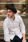 Giovane uomo in elegante giacca bianca e cappello con occhiali alla moda e guardando la fotocamera. — Foto stock