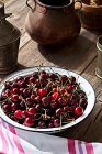 Fresh cherries in metal bowl on brown wooden table — Stock Photo