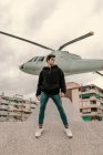 Красивый молодой человек стоит перед памятником вертолёту на городской улице — стоковое фото