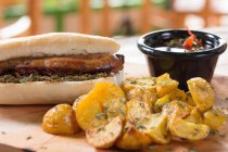Hambúrguer fresco e apetitoso servido com molho e batatas — Fotografia de Stock