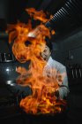 Cocinero emocionado haciendo un flambe en la cocina del restaurante - foto de stock