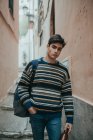 Молодой уверенный подросток в свитере стоит на улице и смотрит в камеру — стоковое фото