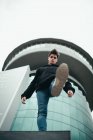 Junger Mann steht vor modernem Gebäude und tritt ab — Stockfoto
