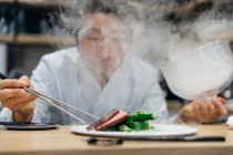 Chef cocinando en restaurante con plato de humo - foto de stock