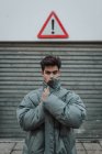 Retrato de adolescente em jaqueta cinza quente em pé sob sinal na rua — Fotografia de Stock