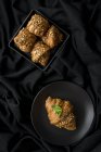 Gebackene Croissants in Schale und auf Teller auf schwarzem Stoff — Stockfoto
