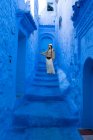 Mulher vestindo boné e saia longa andando na cidade marroquina tingido de azul — Fotografia de Stock