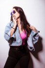 Seducing young pink dressed woman in sunglasses standing at white wall — Stock Photo