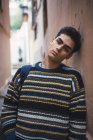 Joven adolescente confiado en suéter de pie en la calle de la ciudad y mirando a la cámara . - foto de stock