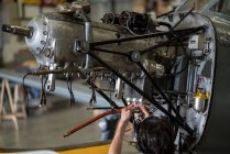 Crop hands of aircraft mechanic fixing engine of small airplane in hangar — Stock Photo