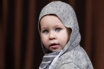 Retrato de adorável pequena criança olhando para a câmera em fundo cinza. — Fotografia de Stock