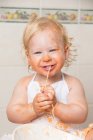 Bambino allegro seduto sul racconto e divertirsi mentre si mangia la pasta dalla ciotola. — Foto stock