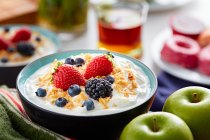 Breakfast bowl of yogurt and berries on table with ingredients — Stock Photo