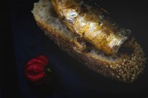 Petit poivron rouge près du pain avec du poisson en conserve sur la poêle — Photo de stock