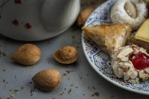 Dulces típicos marroquíes con miel en plato sobre mesa gris con almendras enteras - foto de stock