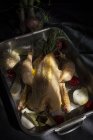 Pollo entero crudo listo para asar en una bandeja para hornear con ingredientes - foto de stock