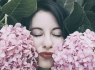 Retrato de mujer morena joven con maquillaje en flores rosadas - foto de stock