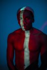 Emotionsloser ethnischer Mann mit heller Linie am Körper und Blick in die Kamera — Stockfoto