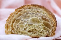 Primo piano di texture spugnosa di delizioso croissant appena sfornato in taglio su tessuto bianco — Foto stock