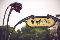 Iscrizione metropolitana scritta in cornice di ferro sullo sfondo di alberi e case, Parigi, Francia — Foto stock