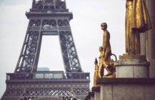 Gold covered statues of people on background of Eiffel Tower, Paris, France — Stock Photo