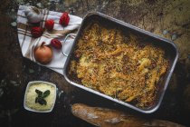 Baked macaroni with cheese and chorizo in baking pan on rustic table with ingredients — Stock Photo