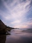 Scogliera rocciosa e acqua di mare sotto cielo drammatico tramonto nuvoloso — Foto stock