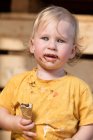 Niño en ropa amarilla comiendo helado de chocolate con cono de gofre. - foto de stock