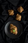 Croissants cuits au four sur assiette et sur tissu noir — Photo de stock