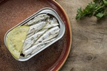 Sardinen in Dosen auf braunem Teller mit Zitrone — Stockfoto