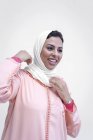 Улыбающаяся марокканка в типичном арабском платье, связывающая хиджаб на белом фоне — стоковое фото